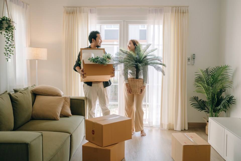 a man and a woman carrying boxes in a living room