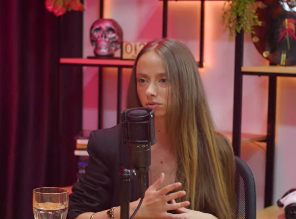 a woman sitting in front of a microphone with the number 012 behind her