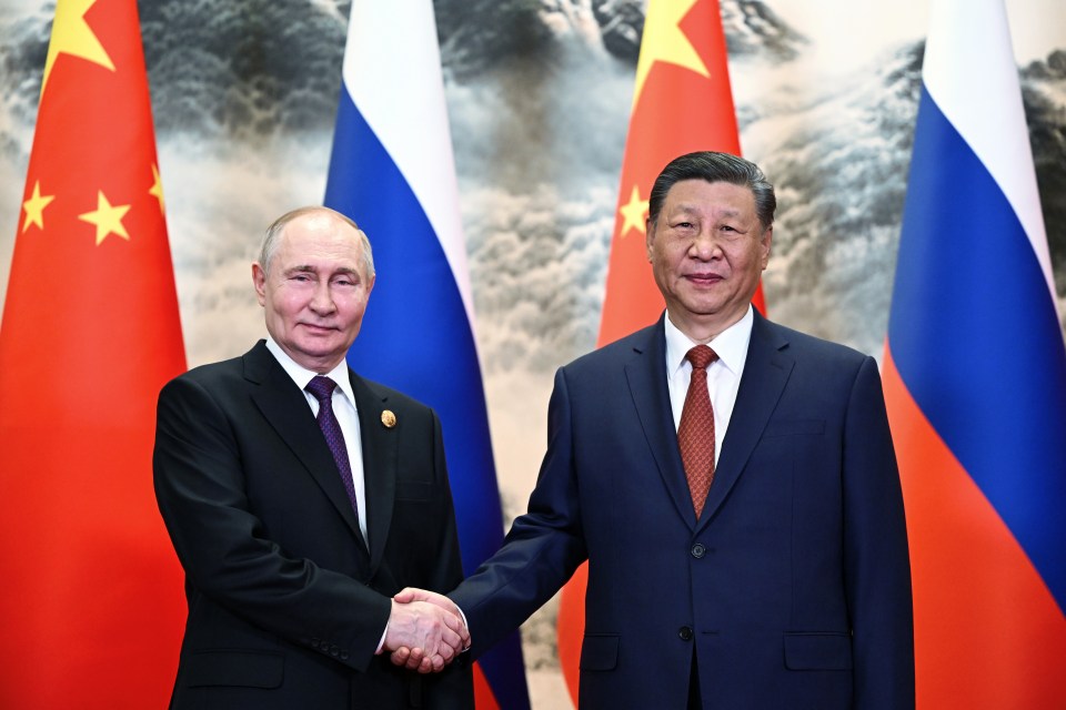 Vladimir Putin and Xi Jinping shake hands as they meet for a summit