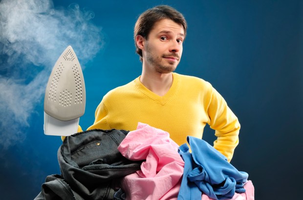 a man in a yellow sweater is ironing a pile of clothes