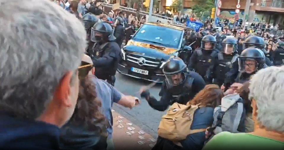 Riot police appear to strike a woman with a baton