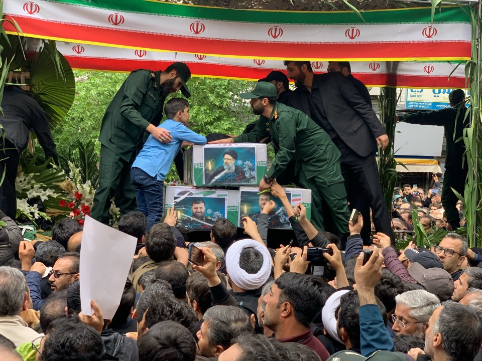 Grievers, including a young boy, reach for the pictures of Raisi and other fallen officials