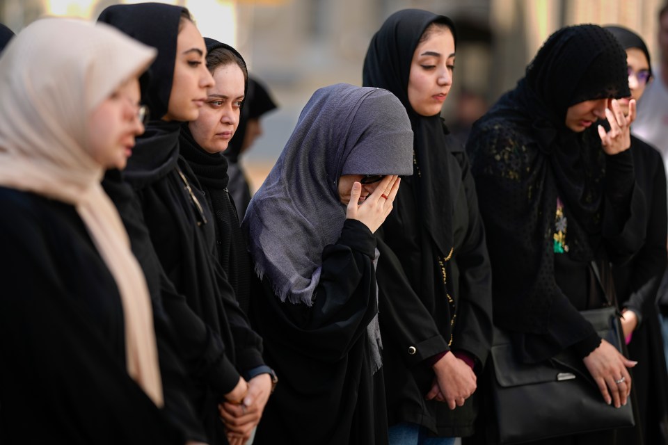 Iranian students who study in Russia react as they stand next to a portrait of President Raisi at a makeshift memorial in Moscow, Russia