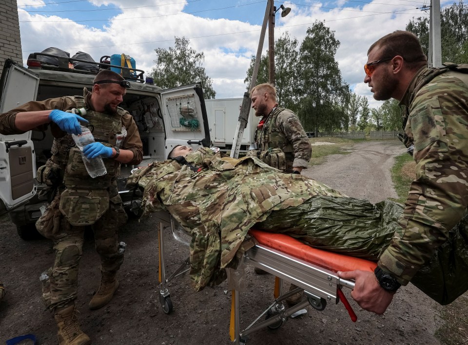 Military paramedics treating a fellow comrade before loading him into an emergency vehicle