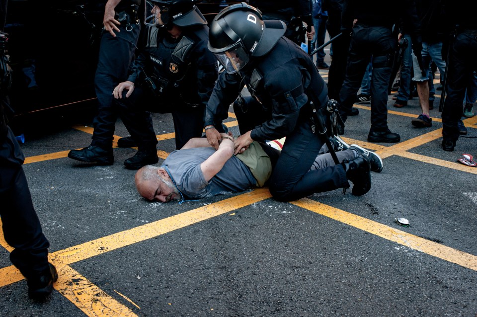 The man is cuffed by a cop while lying face-down on a road