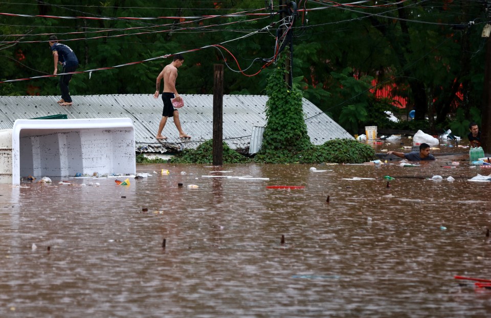 People are stuck on the roofs of their sinking houses to avoid the current