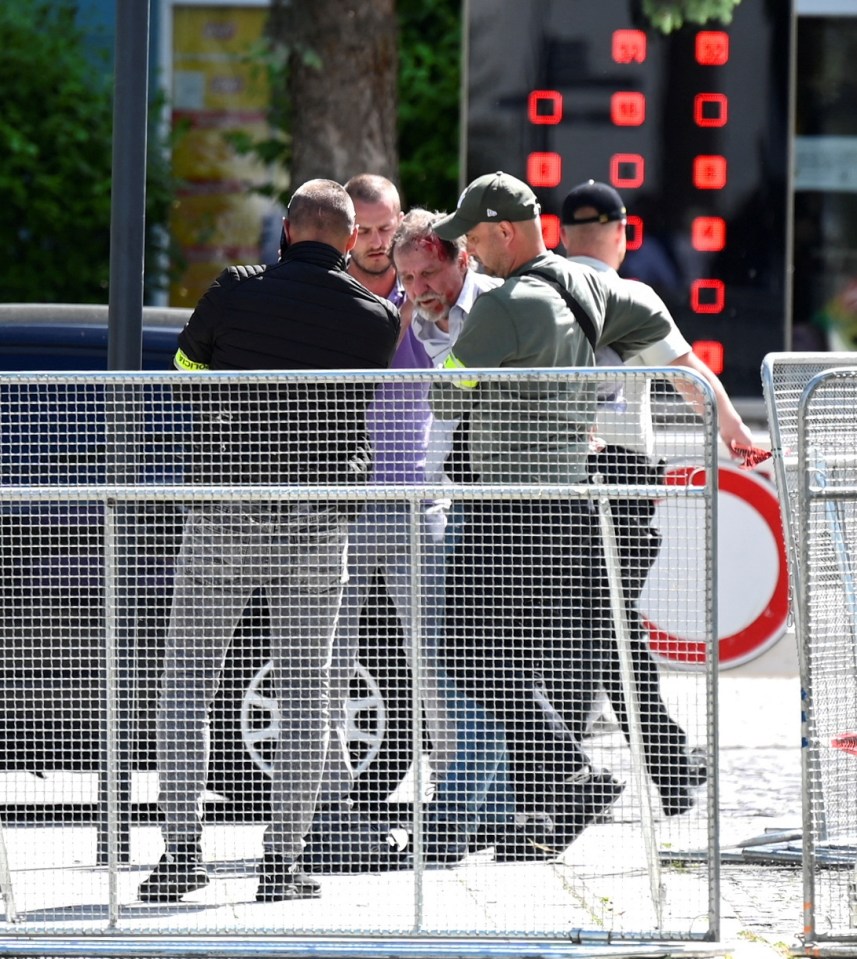 The suspected attacker is seen with blood on his head as he is detained