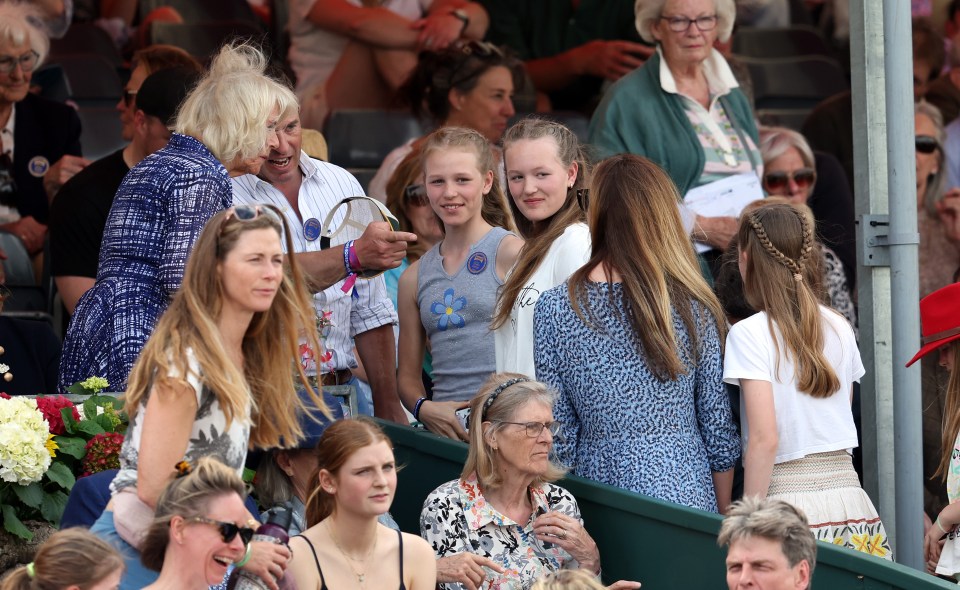 Peter, flanked by his two daughters Savannah and Isla, points towards Harriet as he chats to Queen Camilla