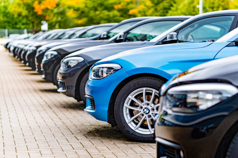 Row of used BMW cars parked at a dealership.