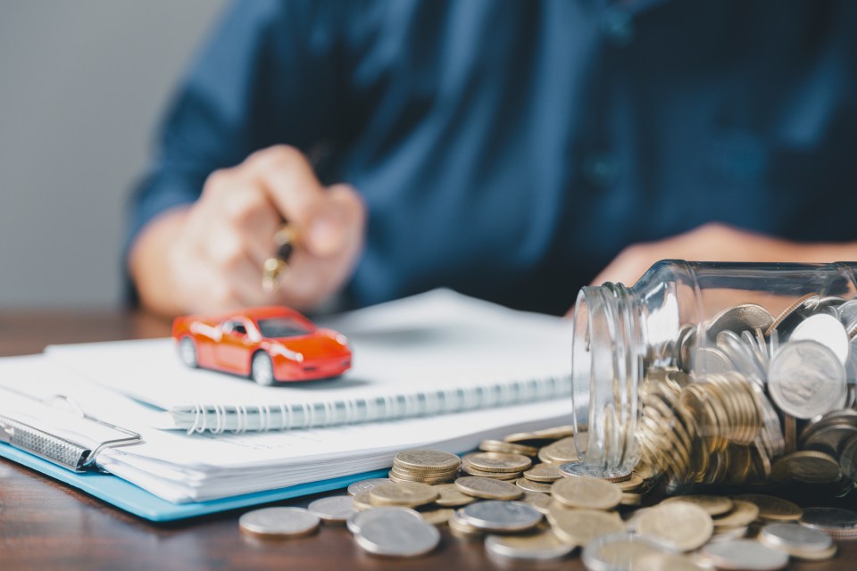 a jar of coins sits on a table next to a red car