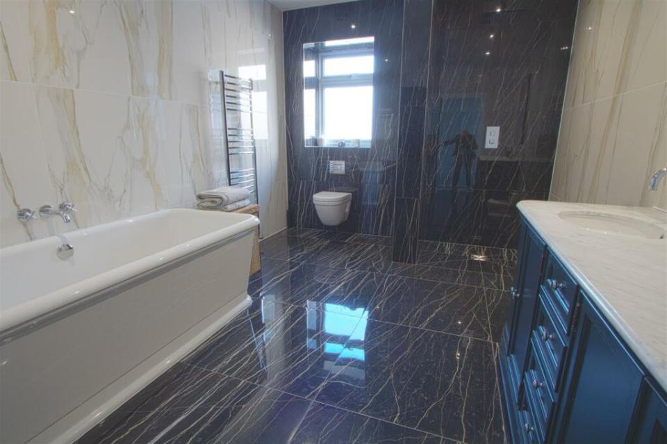 The bathroom is decorated with dark tiles