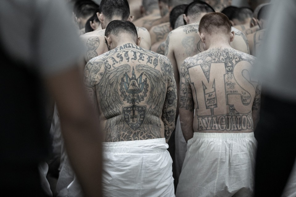 Tattooed gang members made to strip to just white shorts as they line for the transfer