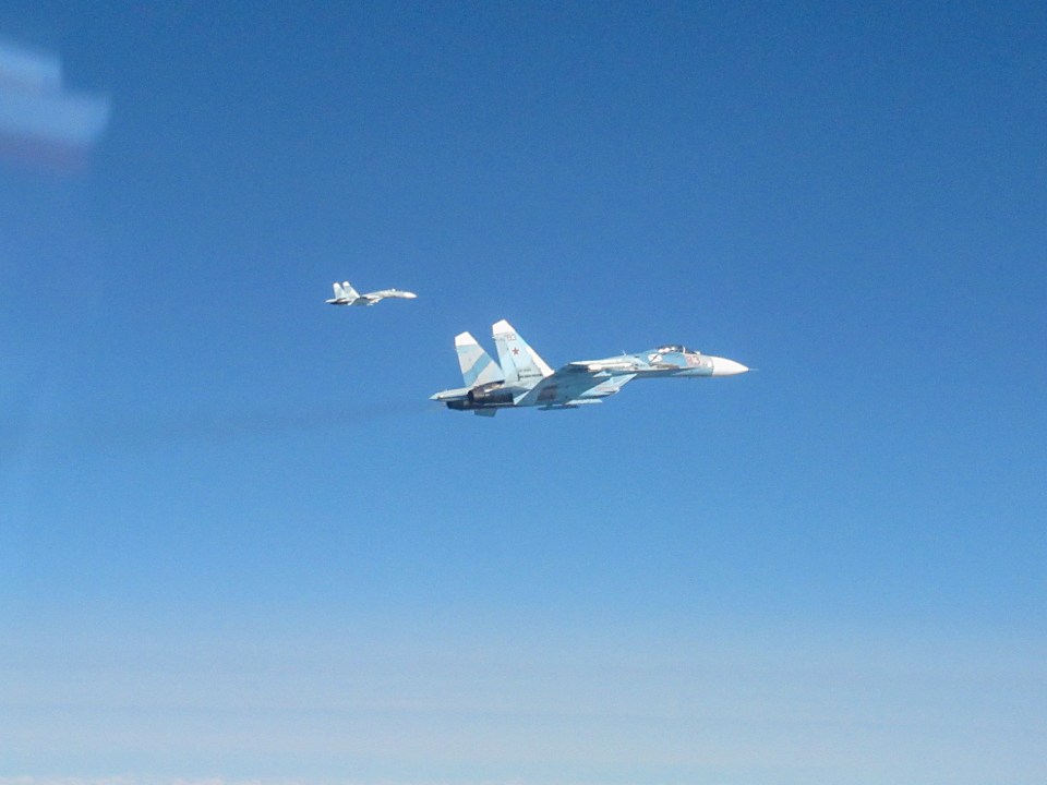 two fighter jets are flying in a blue sky