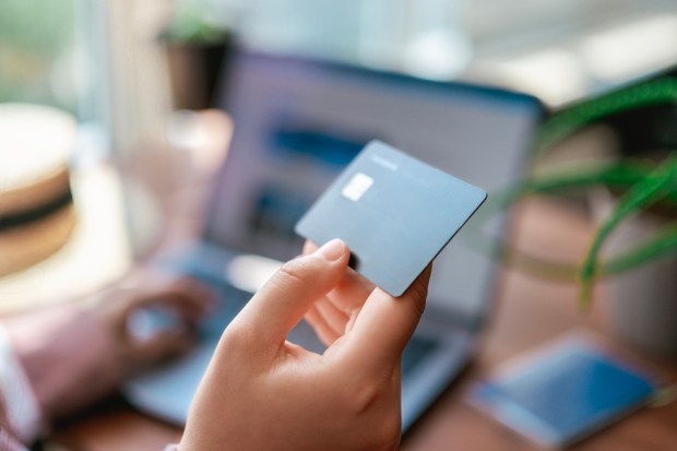 a person holding a credit card in front of a laptop