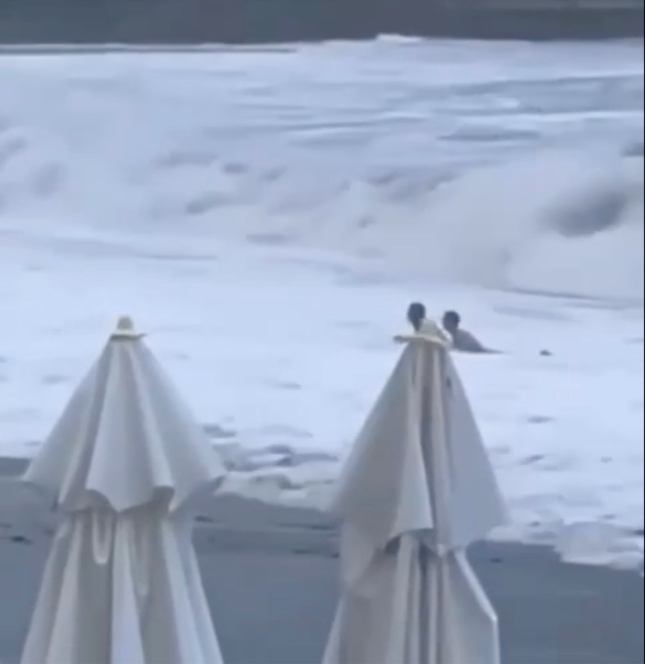 Onlookers see the couple struggle in the thrashing waves