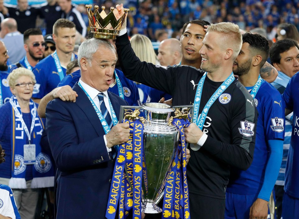 two men holding a trophy with barclays ribbons around them