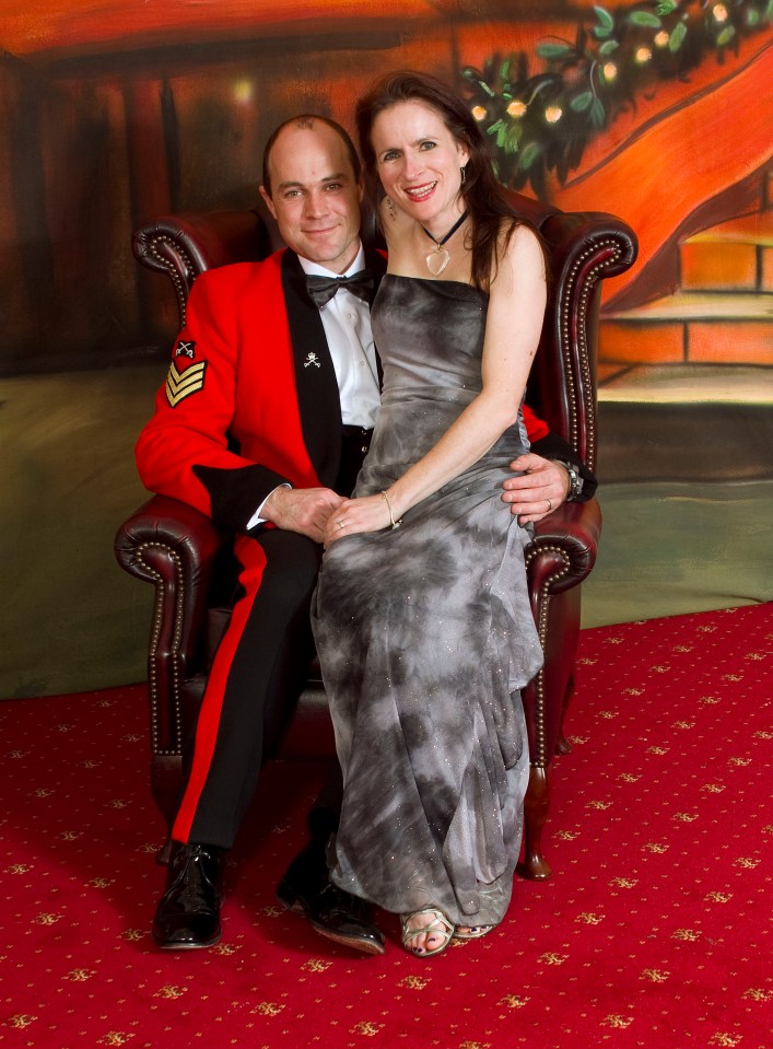 a man in a red jacket sits next to a woman in a grey dress