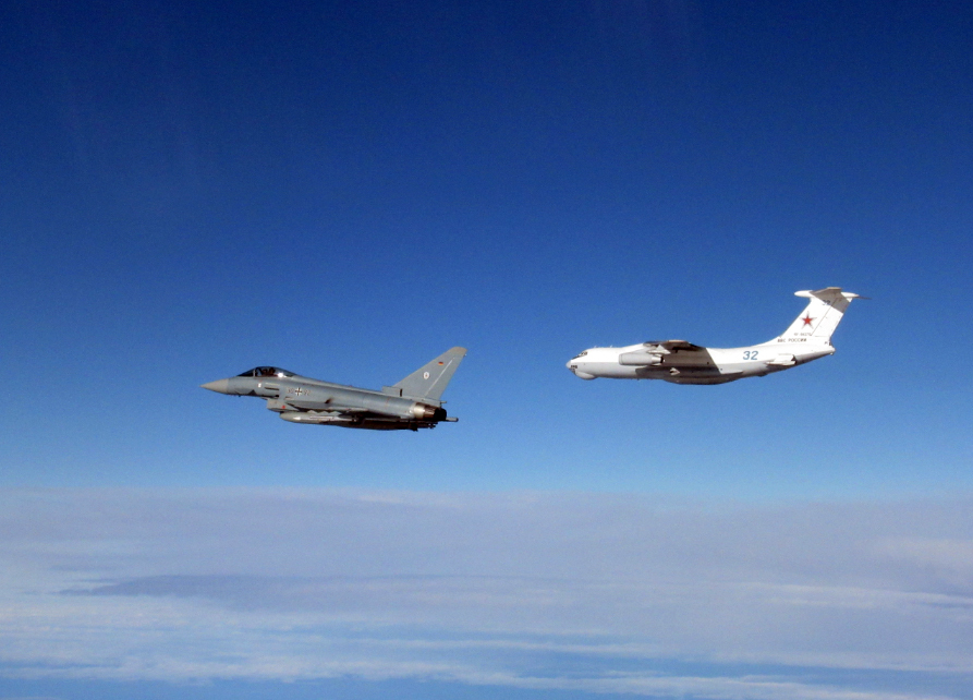 a plane with the number 32 on the tail is flying next to a fighter jet