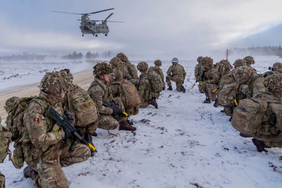 a helicopter flies over a group of soldiers in the snow