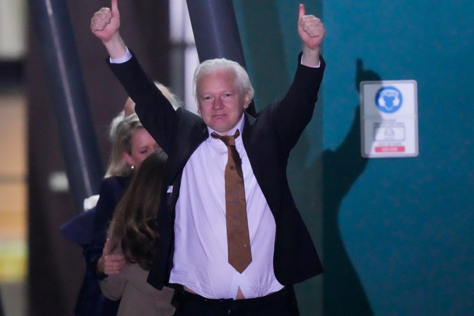 Assange raises his arms in a gesture of victory at the airport