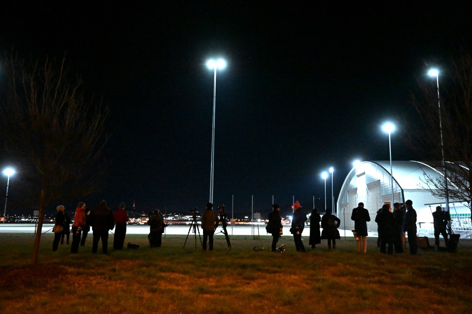 a group of people are standing in a field at night