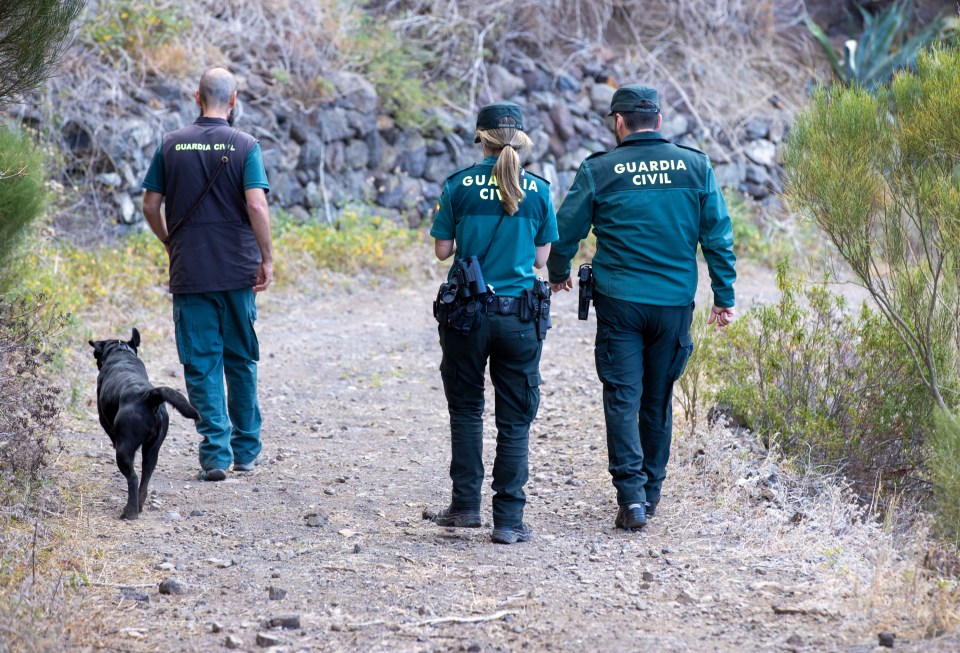 three guardia civil officers are walking down a dirt path