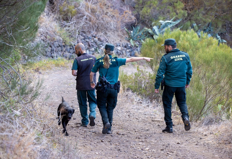 three guardia civil officers are walking down a path