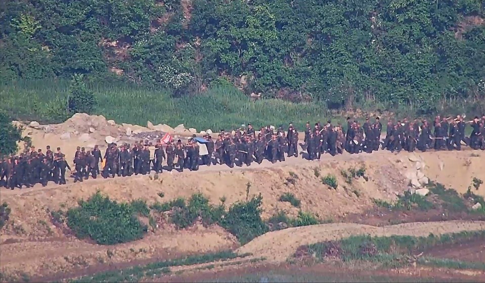 a large group of soldiers marching down a dirt road