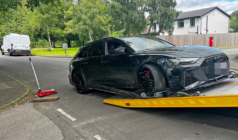 a black audi is on a yellow tow truck