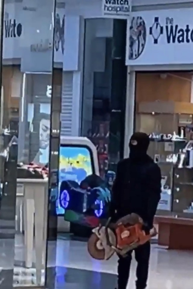 A hooded gang member wields a running circular saw to deter any potential would-be heroes