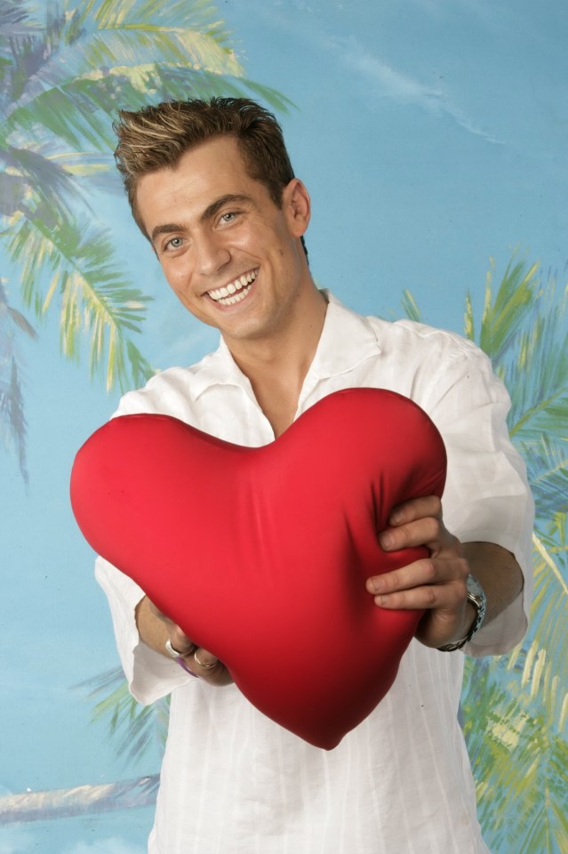 Paul Danan holding a heart-shaped pillow.