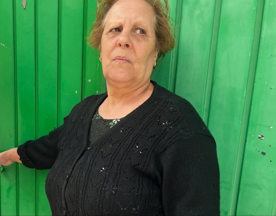 a woman in a black sweater stands in front of a green wall