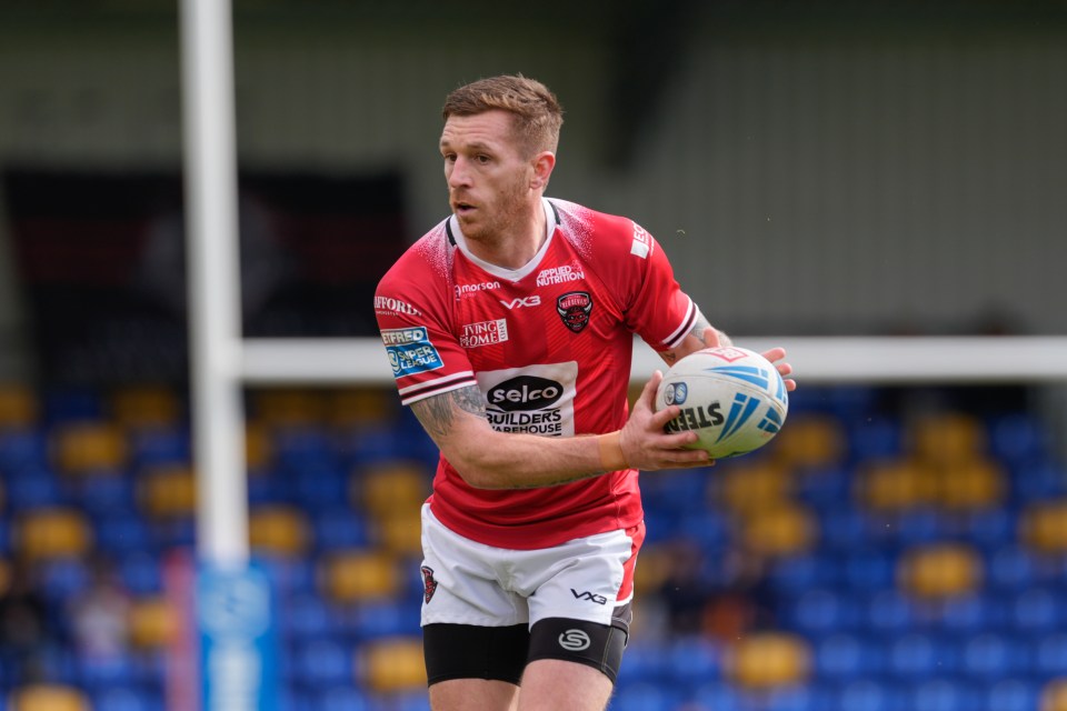 a rugby player wearing a red and white jersey that says selco builders warehouse