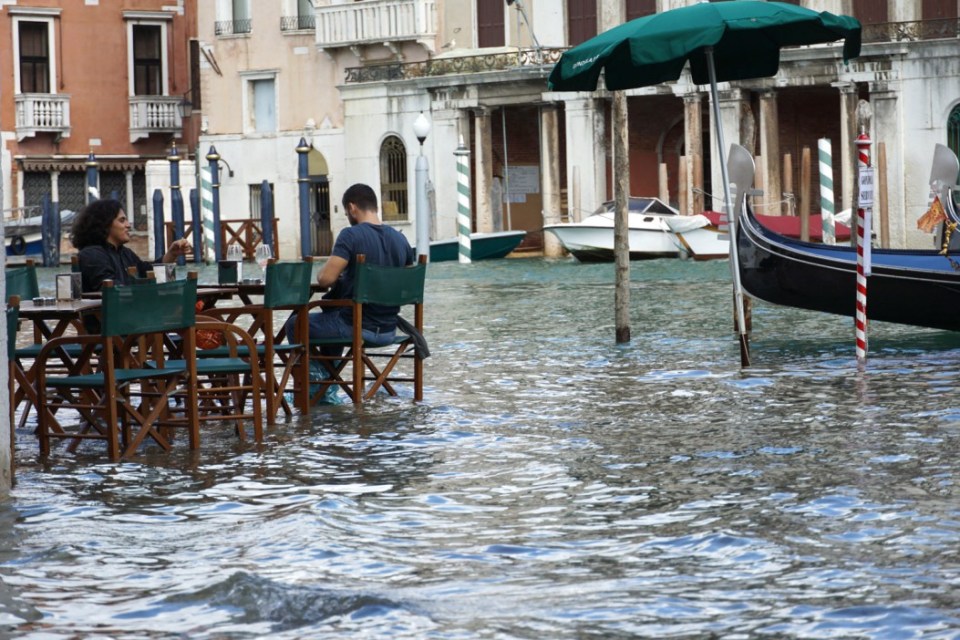 Tourists have a drink while sitting at the table of a street cafe in Venice in 2020 after severe floods hit