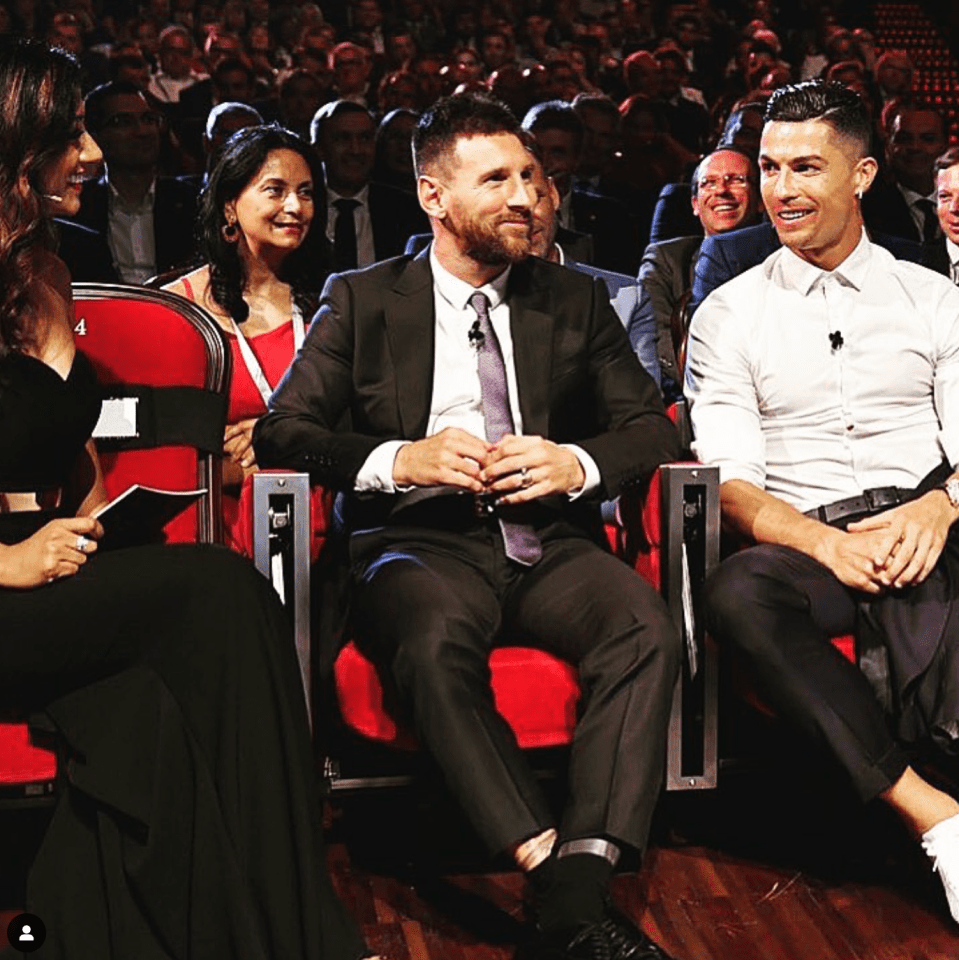 a man in a suit sits next to a man in a white shirt