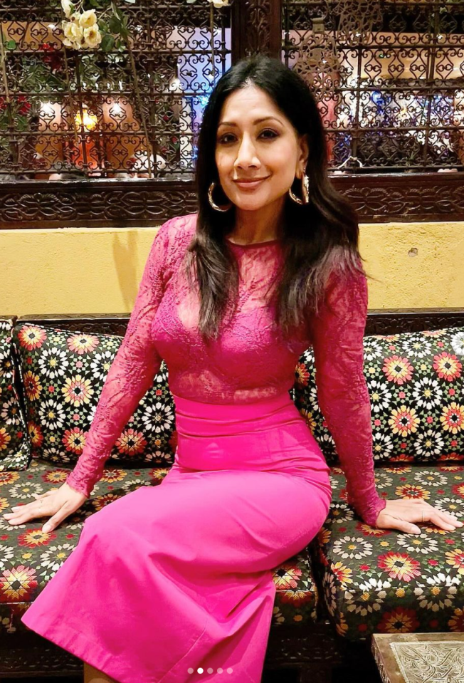 a woman in a pink dress sits on a couch