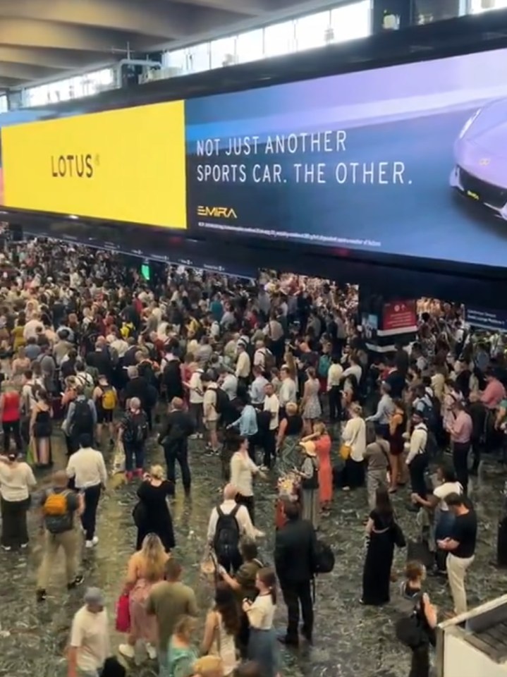 a large crowd of people are gathered in front of a large billboard that says not just another sports car the other