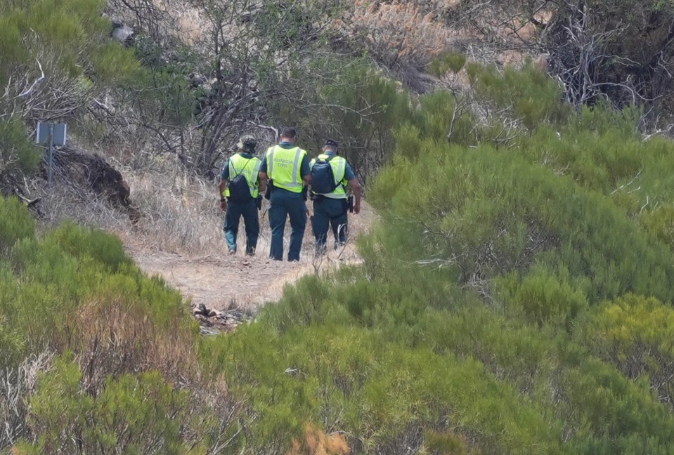 a group of police officers are walking down a dirt path