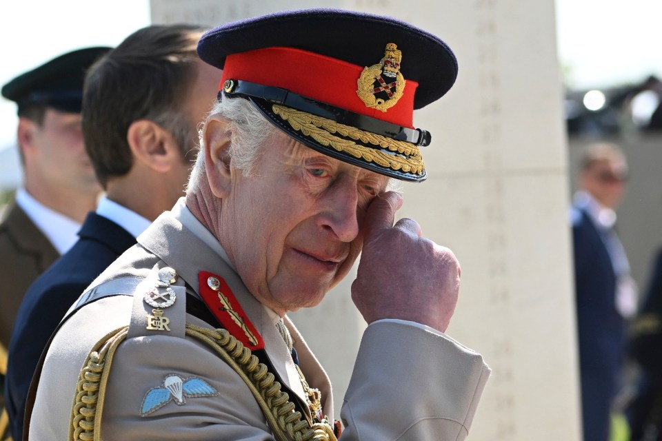 Charles wipes his eye by the memorial wall