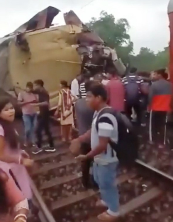 People crowd around the wreckage on the tracks