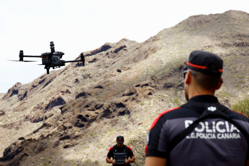 a man in a policia canaria uniform looks at a drone