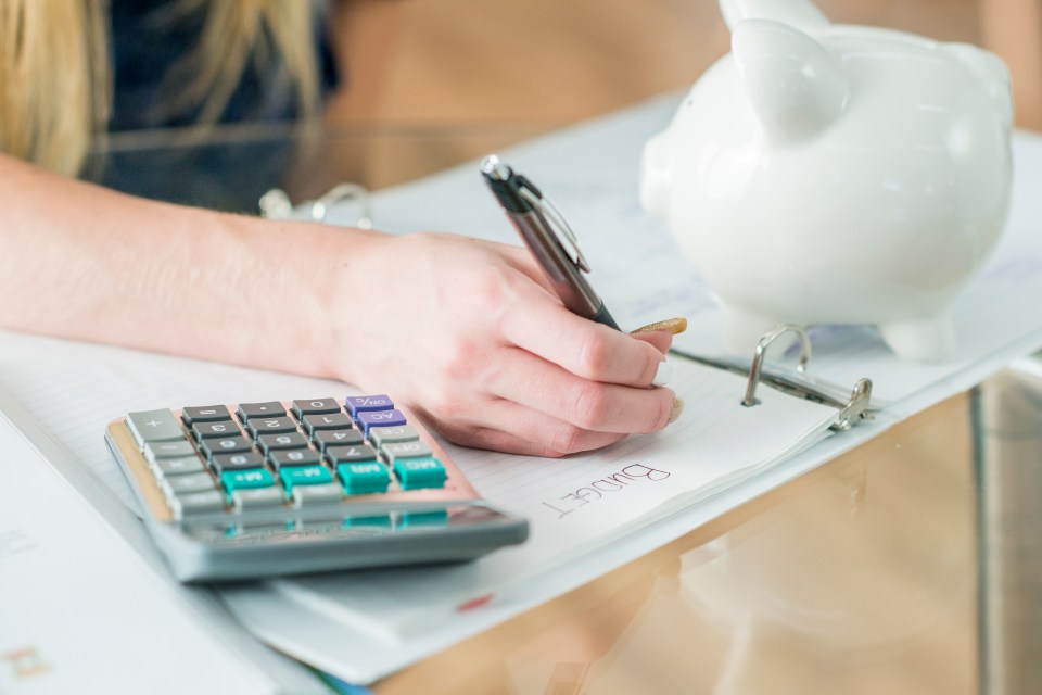 a person is writing on a piece of paper that says budget