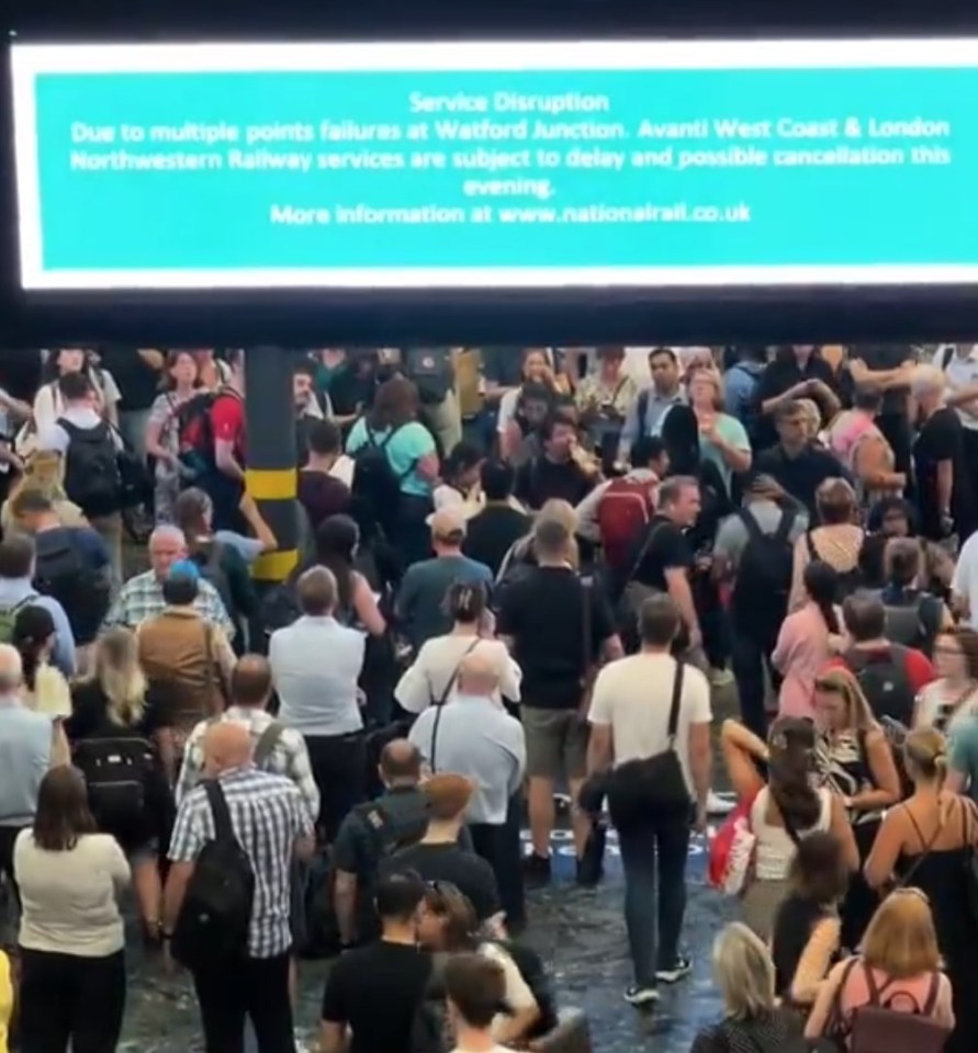 a crowd of people are gathered in front of a large screen that says service disruption