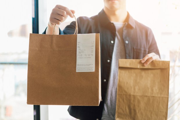 a man is holding a brown paper bag with a receipt on it