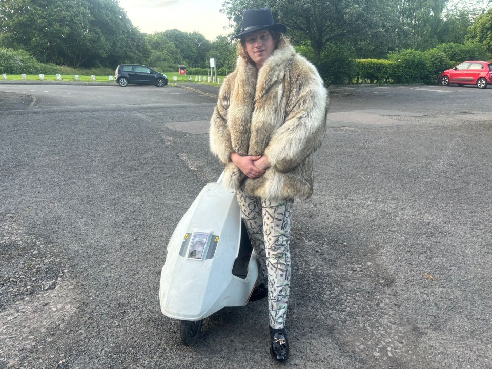 a man in a fur coat stands next to a white scooter