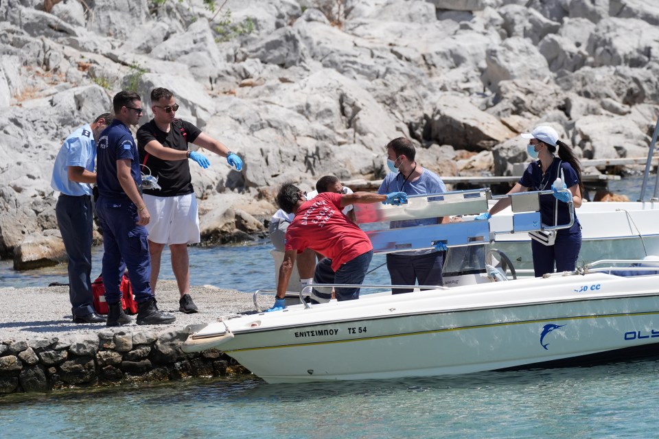 Emergency services lifting an empty stretcher off a boat at Agia Marina after the body was found