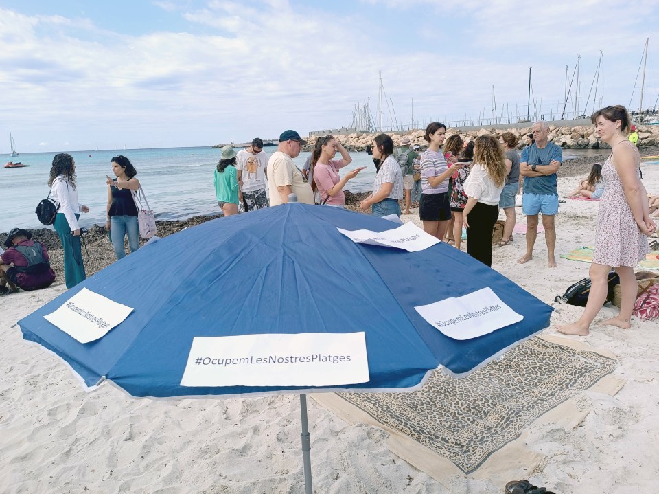 Protesters gather near umbrellas with the slogan: 'We occupy our beaches'