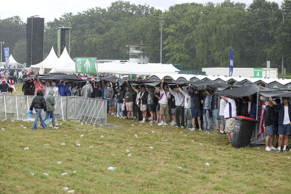 Supporters could be seen sheltering - pints in hand - under tarp sheets in one fan zone