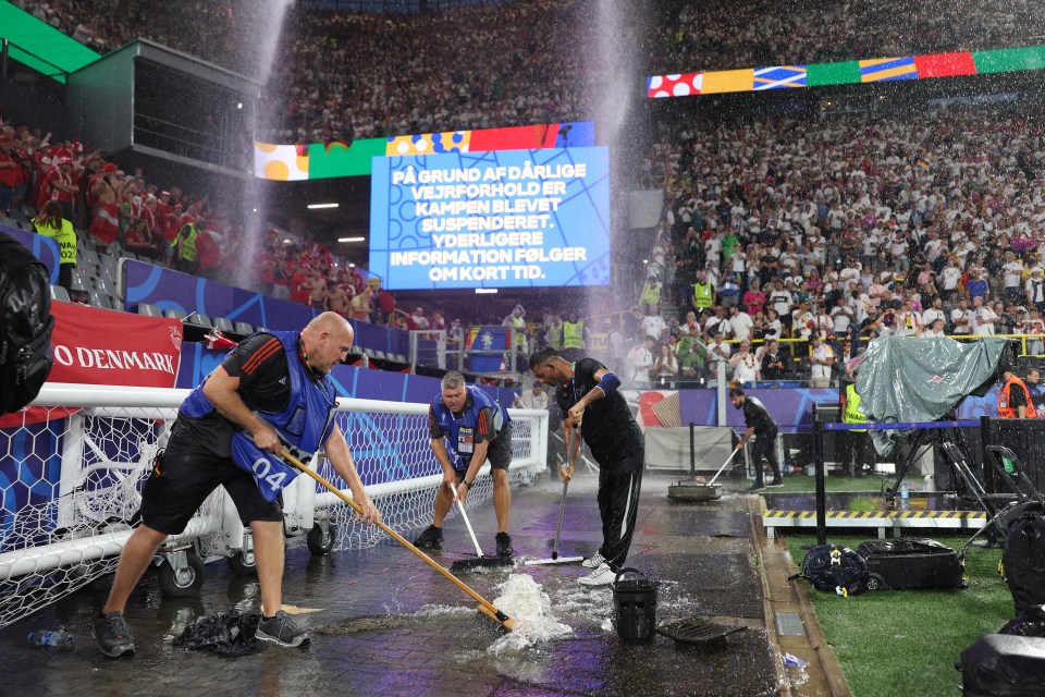 Stadium staff swept water off the sidelines