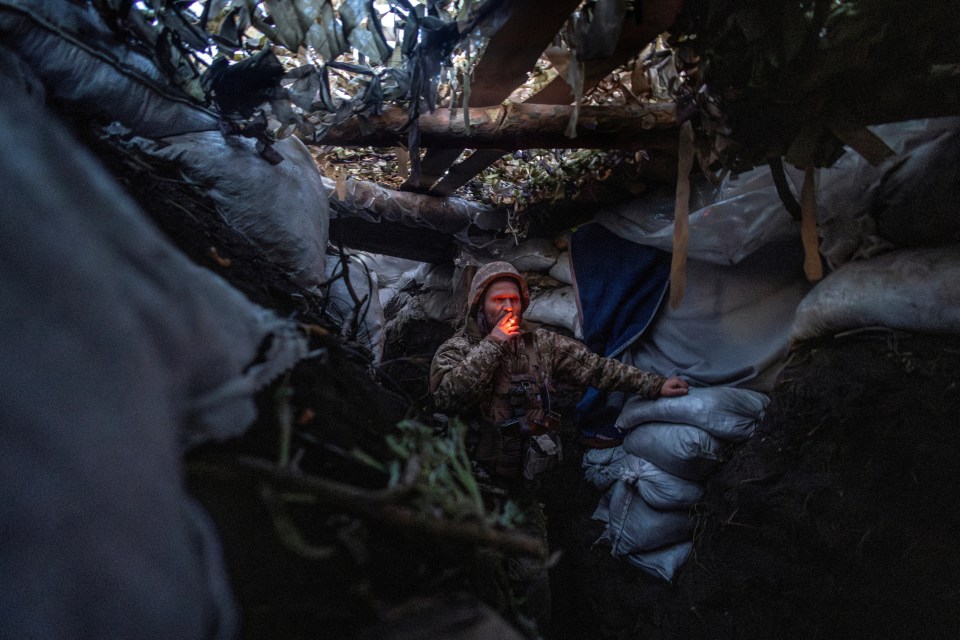 Infantry soldier Viktor of Ukraine’s 58th Motorised Brigade smokes while standing in a frontline trench in the Donetsk region